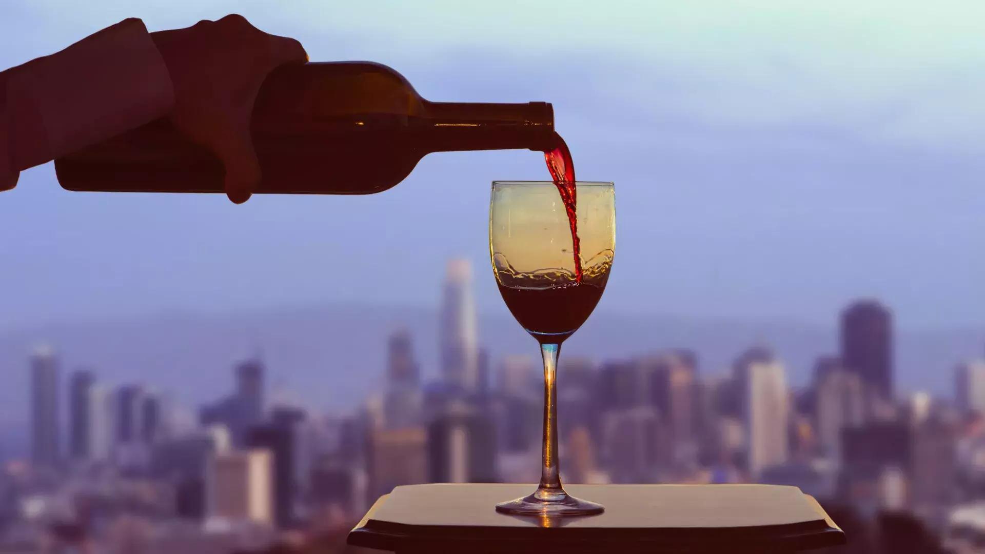 一杯红酒被端上餐桌，窗外是贝博体彩app的天际线。.