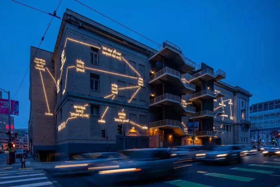Um prédio 在贝博体彩app é iluminado 和 luz artística do artista Joseph Kosuth
