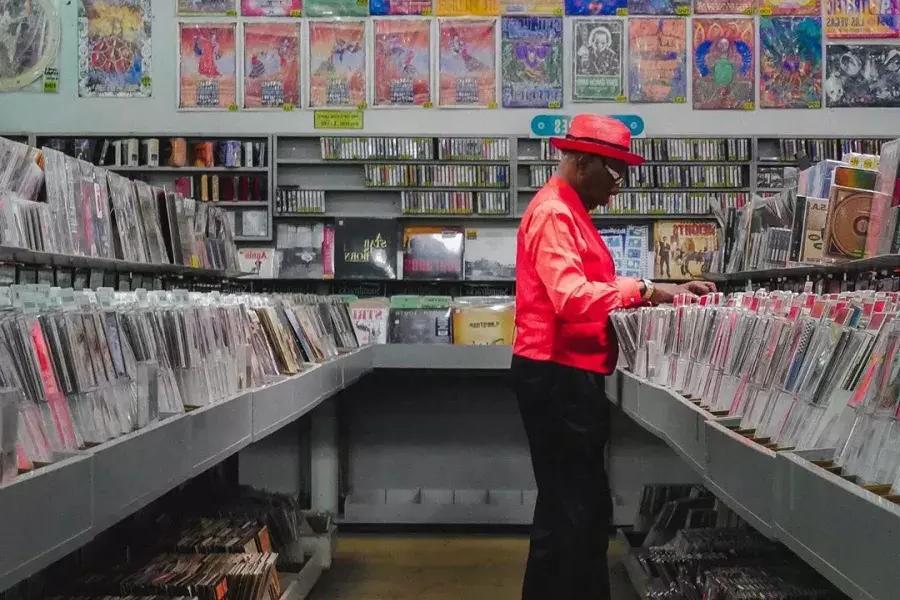 赤いジャケットを着た男性がサンフランシスコのアメーバ・レコードでレコードを買っている。