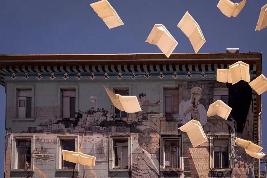 贝博体彩app城市之光书店的外景，墙上画着书和漂浮的纸。.