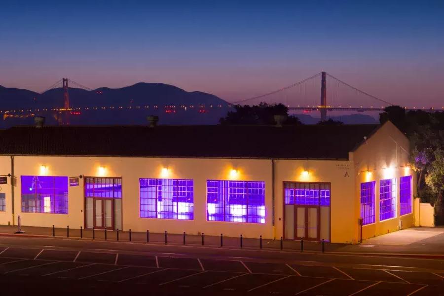 晚上以桥为背景的紫色室内照明会照亮Fort Mason大楼.