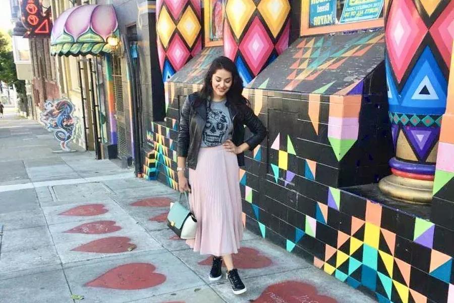 一个女人站在涂有红心的人行道上, em frente a uma vitrine colorida, no bairro de Haight-Ashbury, em São Francisco.
